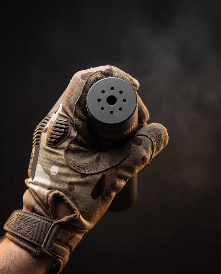 Торець глушника NEMESIS CORE 5.56 чорний матовий у рукавиці - вид на вихідний канал і газові отвори