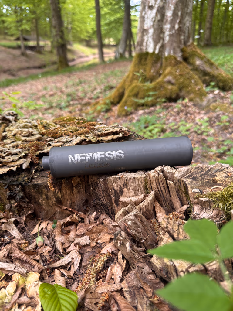Глушник NEMESIS CORE 7.62×39 на замшілому пні, великий план гравіювання NEMESIS на корпусі