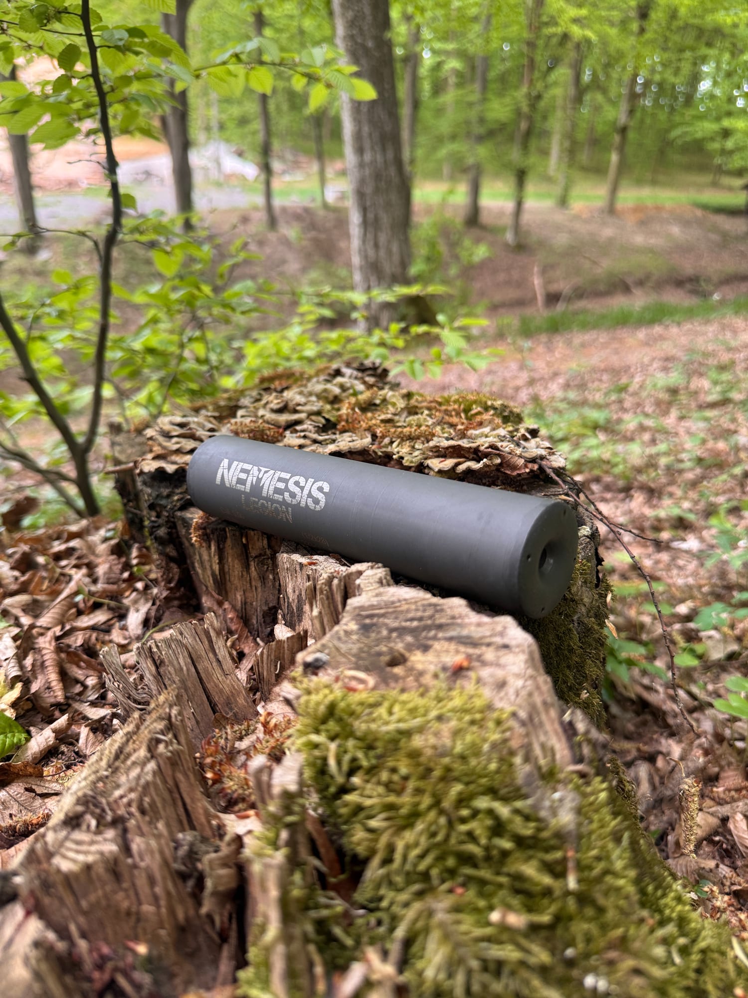 Монолітний глушник NEMESIS CORE 7.62 на пні, видно торець із вихідним каналом і написом NEMESIS