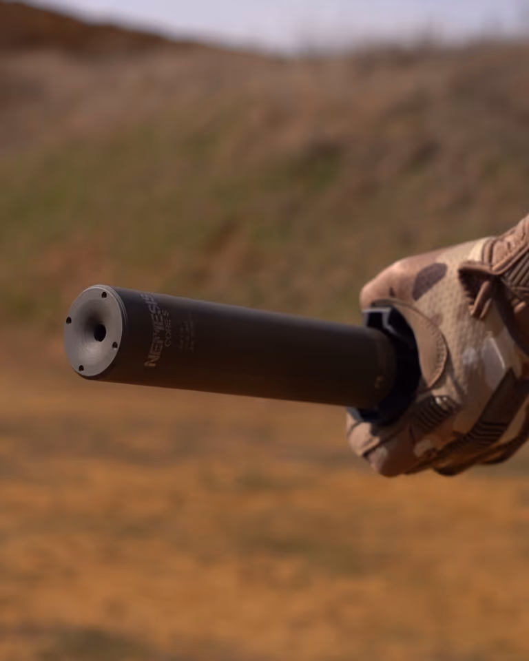 Саундмодератор NEMESIS CORE 9mm чорний у тактичній рукавиці - вид на торець і гравіювання NEMESIS CORE збоку