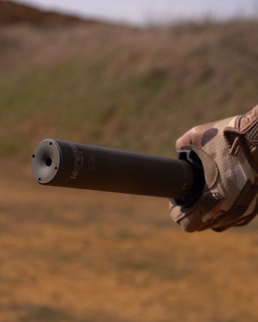 Саундмодератор NEMESIS CORE 9mm чорний у тактичній рукавиці - вид на торець і гравіювання NEMESIS CORE збоку