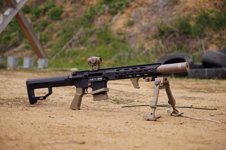 Глушник NEMESIS CORE Internal 5.56 на цівьо AR-15 у руці в тактичній рукавиці - вид зверху, видно торець і газові отвори
