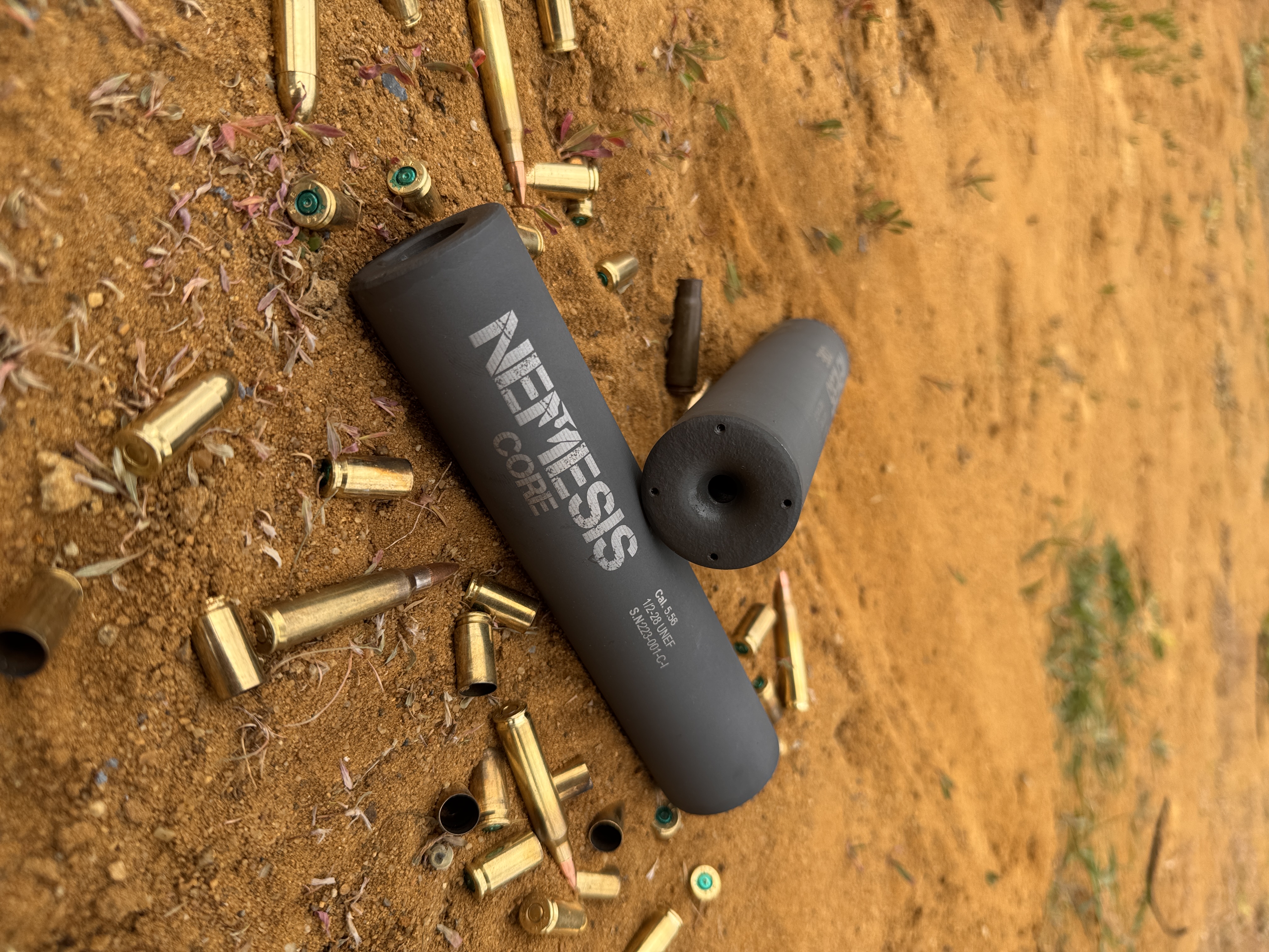 Розібраний глушник NEMESIS CORE Internal 5.56 на стрільбищі: корпус із написом NEMESIS CORE і знятий ДГК поруч
