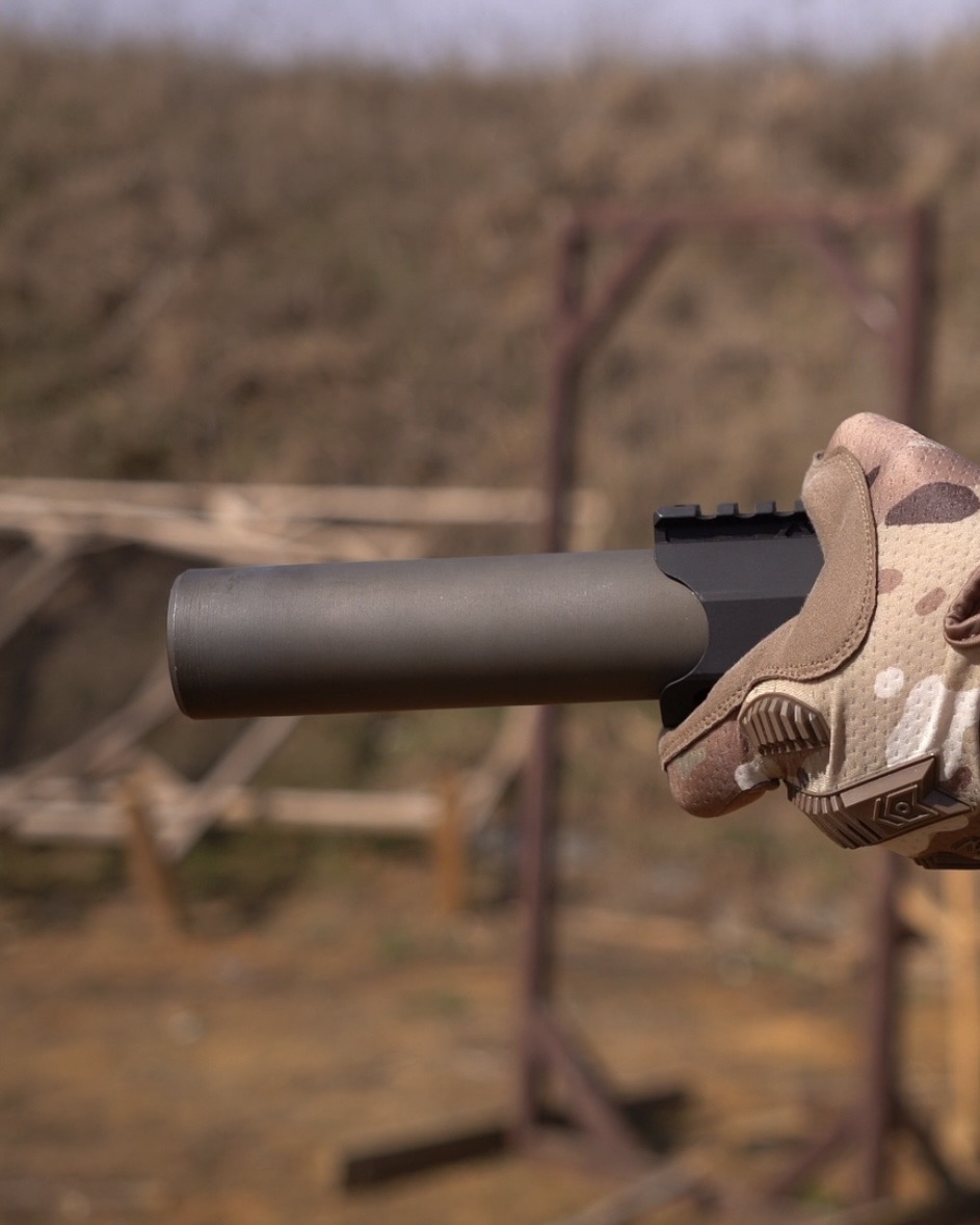 Глушник NEMESIS CORE Internal 5.56 у тактичній рукавиці на полігоні, вид збоку - торець із вихідним каналом крупним планом