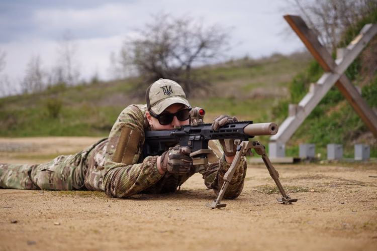 Стрілець на вогневому рубежі з AR-15 5.56 на сошках і глушником NEMESIS CORE, вид спереду-збоку