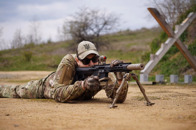 Стрілець із NEMESIS CORE 9mm на PCC прицілюється лежачи зі сошками, вид збоку на полігоні
