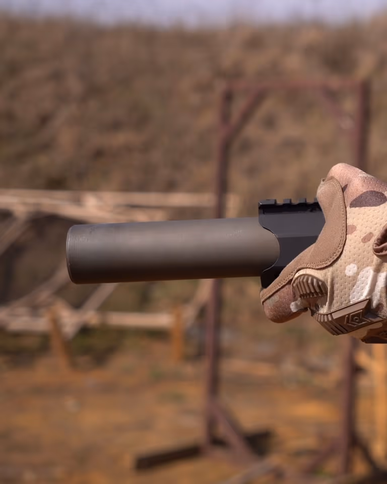 Глушник NEMESIS CORE 9mm на PCC у тактичній рукавиці, вид збоку крупним планом - чорний матовий корпус