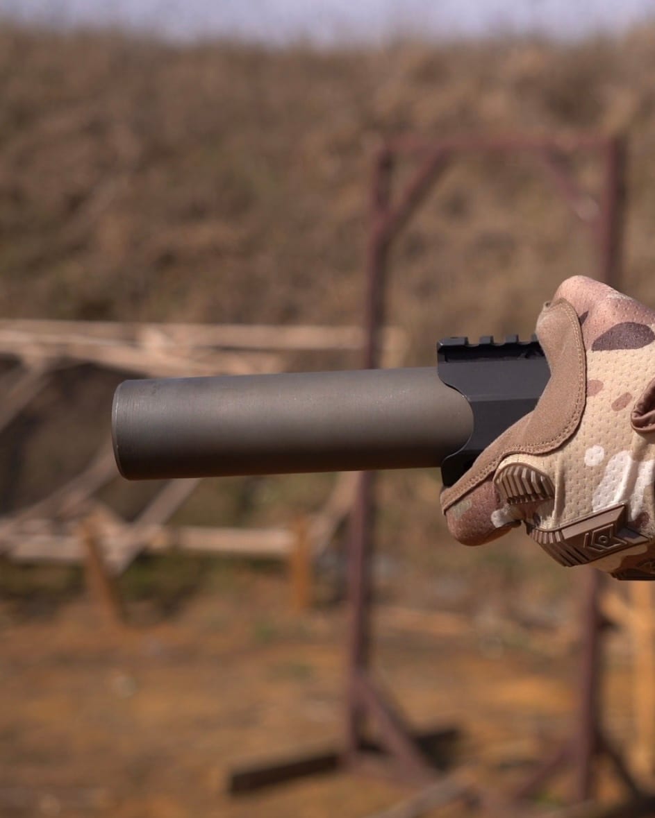 Глушник NEMESIS CORE 9mm на PCC у тактичній рукавиці, вид збоку крупним планом - чорний матовий корпус