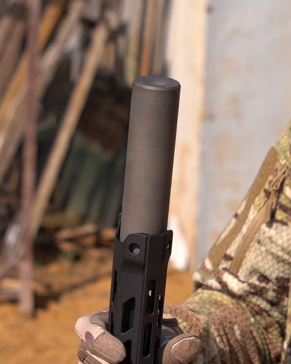 Вид на торець глушника NEMESIS CORE 9mm, накрученого на PCC, у тактичній рукавиці - видно вихідний канал