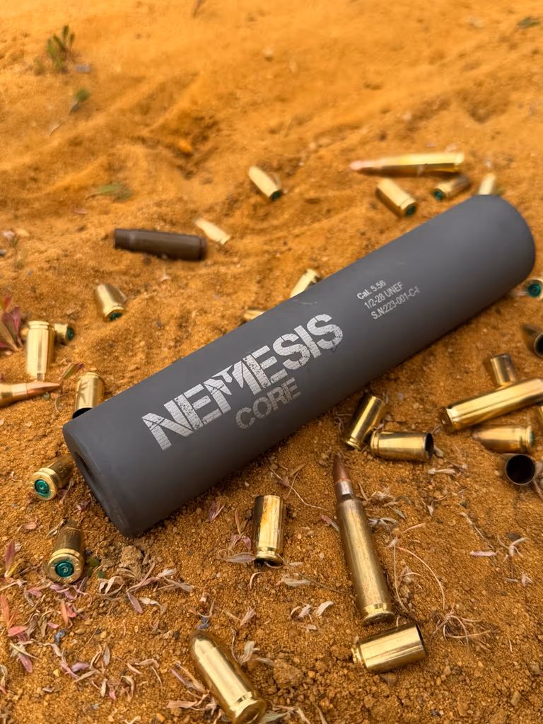 Глушник NEMESIS CORE 9mm чорний матовий лежить серед стріляних гільз - добре видно гравіювання NEMESIS CORE